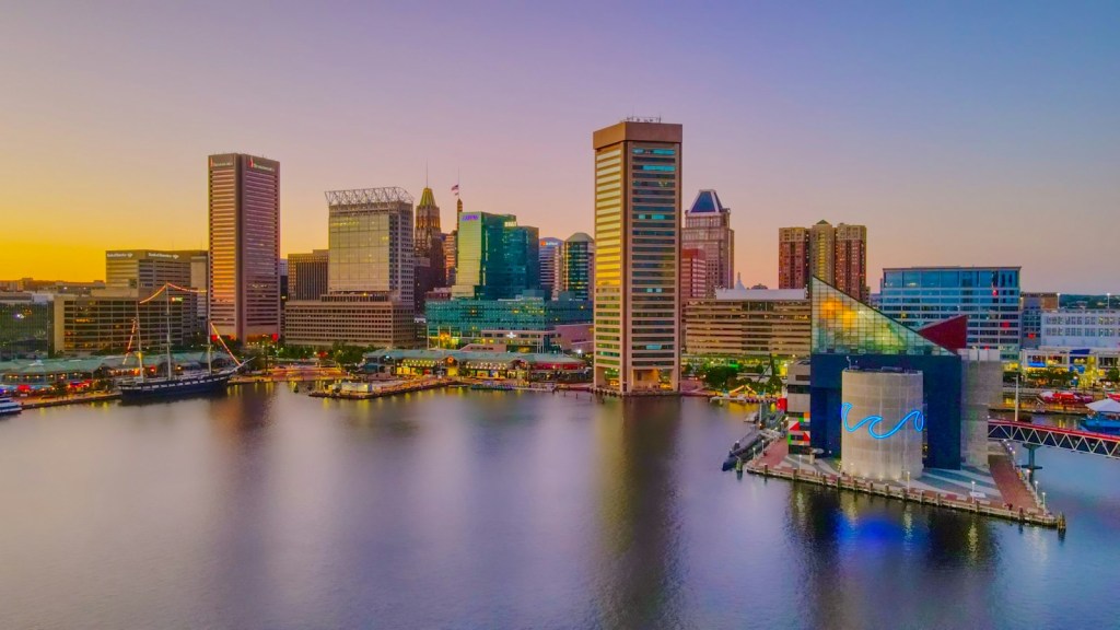Baltimore's Inner Harbor skyline at sunset, seen from above the water